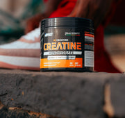 Pot de Créatine Monohydrate GFit Series posé sur un muret devant des baskets, créatine en vente chez Galsenfit à Dakar